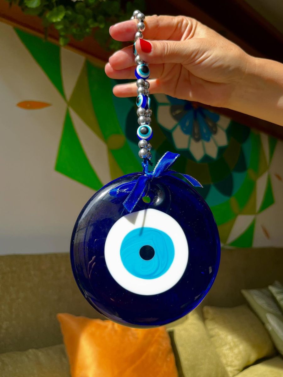 Ojo turco azul colgando frente al mural de mandala pintado en el centro.